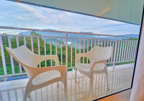 a balcony with two chairs and a view of the ocean at Ice Mist Pool Resort Munnar By VOYE HOMES in Munnar