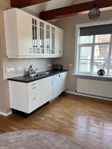 a kitchen with white cabinets and a sink and a window at Bjarnabúð in Húsavík