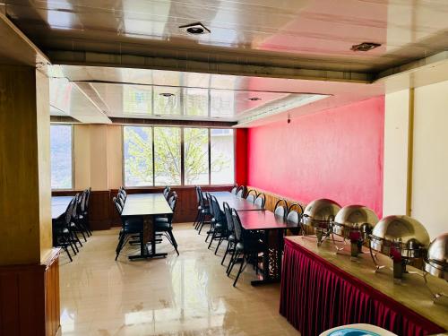 a dining room with tables and chairs and a red wall at Cliff View Residency Lachung in Lachung