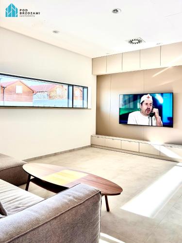 a living room with a tv on the wall at Pod Brzozami Apartamenty Let's Sea Gąski in Gąski