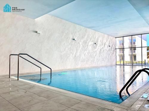 a large swimming pool in a building at Pod Brzozami Apartamenty Let's Sea Gąski in Gąski
