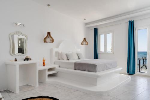 a white bedroom with a bed and a mirror at Manios Suites in Agia Anna Naxos