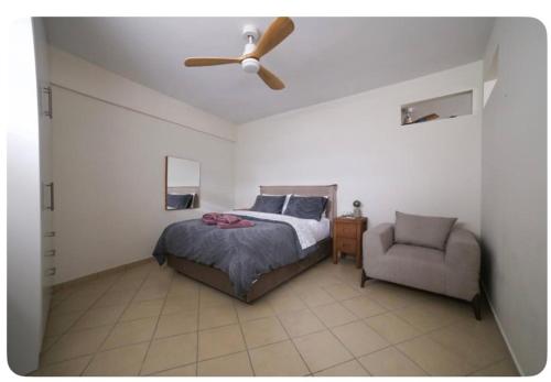 a bedroom with a bed and a ceiling fan and a chair at Home4U apt1, just 8Km from airport in Markopoulo