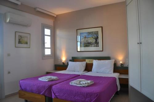 a bedroom with two beds with purple sheets at Helen Suites in Limín Khersonísou