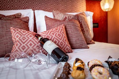 a bottle of wine sitting on a bed with pillows at Hotel Duomo Firenze in Florence