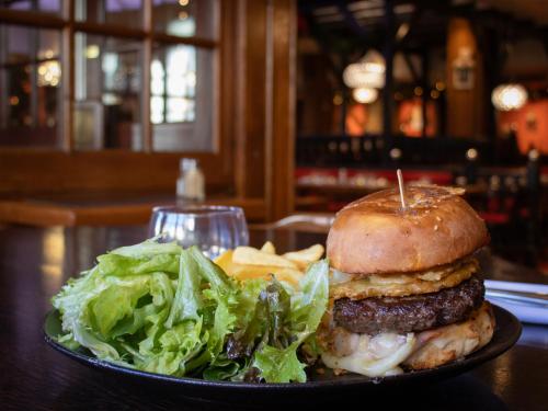 a hamburger and a salad on a black plate at ibis Styles Le Puy en Velay in Le Puy en Velay