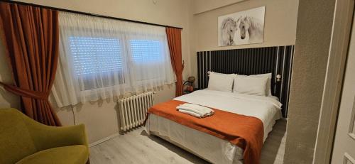 a bedroom with a bed and a chair and a window at Gökçen Çiftliği Pansiyon in Eceabat
