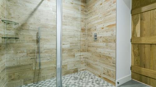 a bathroom with a shower with wooden walls at Swn y Mor Trefadog in Llanfaethlu