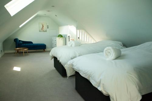 a attic bedroom with two beds with white sheets at Starbright Cottage in Peebles