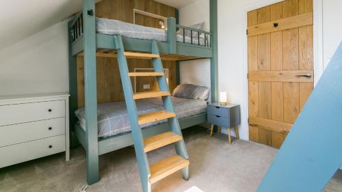 a bunk bed room with two bunk beds and a door at Swn y Mor Trefadog in Llanfaethlu
