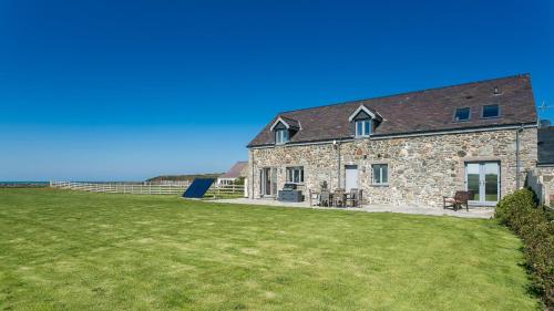 a stone house with a grass yard in front of it at Swn y Mor Trefadog in Llanfaethlu