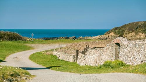 a stone wall and a road next to the ocean at Swn y Mor Trefadog in Llanfaethlu