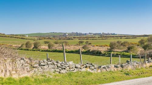 a field with a fence and a stone wall at Swn y Mor Trefadog in Llanfaethlu
