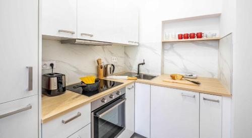 une cuisine blanche avec des armoires blanches et un évier dans l'établissement Cosy Studio in the heart of Belleville, à Paris