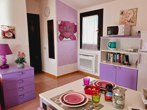 una cocina con paredes moradas y una mesa con platos. en Case Vacanza Santa Teresa Gallura, en Santa Teresa Gallura