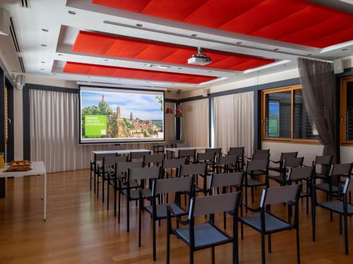 a conference room with chairs and a projection screen at ibis Styles Le Puy en Velay in Le Puy en Velay