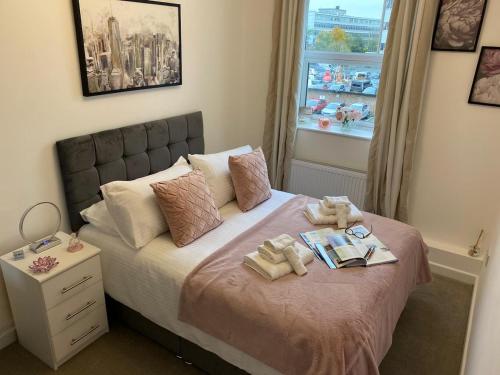 a bedroom with a bed with two towels and a window at Charming 2- Bedroom Apartment in Watford