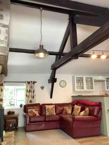 ein Wohnzimmer mit einer roten Couch in einem Zimmer in der Unterkunft Woodland Cottage in Faux-la-Montagne