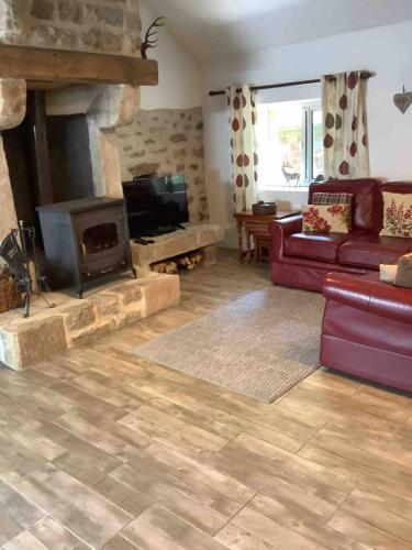 ein Wohnzimmer mit Sofa und Kamin in der Unterkunft Woodland Cottage in Faux-la-Montagne