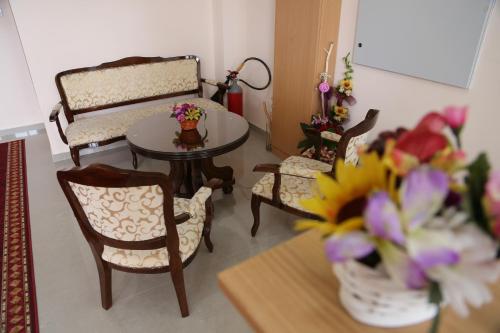 a living room with a table and chairs and flowers at Hotel Novella Uno in Novi Banovci
