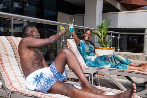 two men sitting in lawn chairs on a patio at Azalaï Hôtel Abidjan in Abidjan
