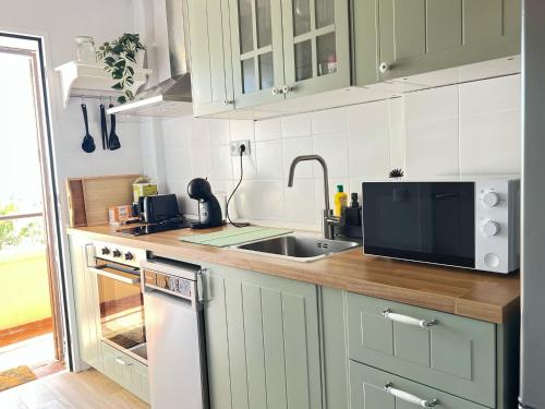 a kitchen with green cabinets and a sink and a microwave at Calypso Holidays II in Sitio de Calahonda