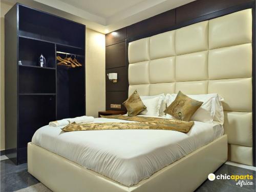 a bedroom with a large bed with a large padded headboard at Chic studio with parking near the airport in Douala