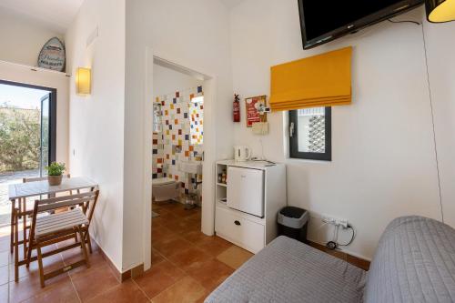 a room with a kitchen with a table and a refrigerator at Amado Properties in Carrapateira