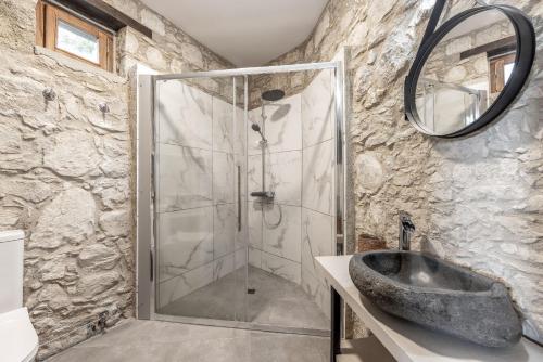 a bathroom with a shower with a stone wall at Casale Xenia in Lyso