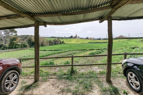 a car parked under a pergola with a view of a field at Habitacions Mas Fuselles in Girona