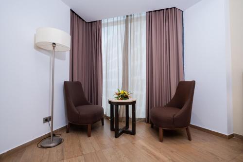 a room with two chairs and a table with flowers on it at Azalaï Hôtel Abidjan in Abidjan