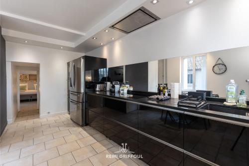 Il comprend une cuisine équipée d'un comptoir noir et d'un réfrigérateur. dans l'établissement Family Stay - In the Heart of Honfleur 8 guests Private Garden, à Honfleur