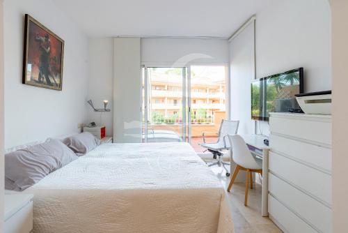 ein weißes Schlafzimmer mit einem Bett und einem Tisch und Stühlen in der Unterkunft Jardines de Santa Maria Golf in Marbella