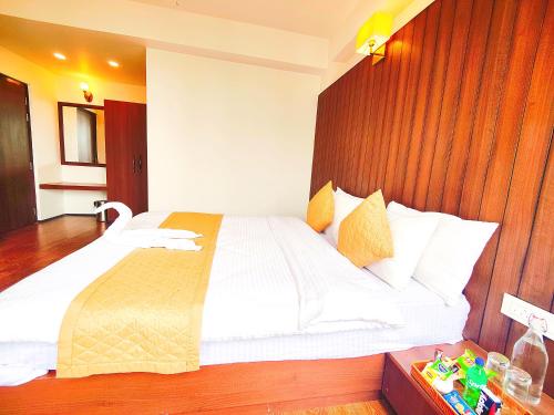 a bedroom with a large white bed with a wooden headboard at Jo'stel Dream Glory Hotel and Bar - Near MG Marg in Gangtok