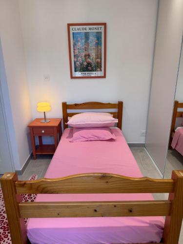 - une chambre avec un lit en bois et des draps roses dans l'établissement Appartement au cœur du village, à Murato