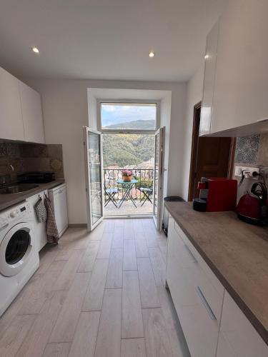 une cuisine avec une porte donnant sur un balcon avec une table dans l'établissement Appartement au cœur du village, à Murato