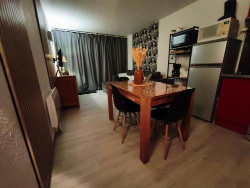 une cuisine avec une table et des chaises dans une pièce dans l'établissement Apt T2, 34m2, pied de piste, 4 à 6 pers, 1 chambre, parking privé sousterrain, à La Mongie