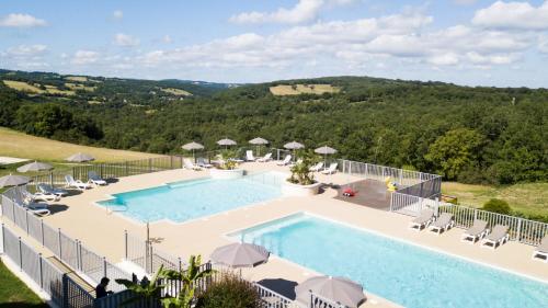 une grande piscine avec chaises et parasols dans l'établissement Domaine de la Faurie, à Séniergues