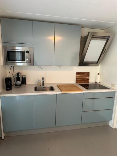 a kitchen with white cabinets and a sink and a microwave at Vakantiewoning Kijkduinpark in The Hague