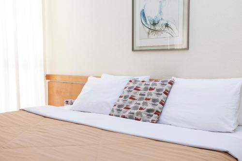 a bed with white sheets and a pillow on it at Nikkey Palace Hotel in Sao Paulo
