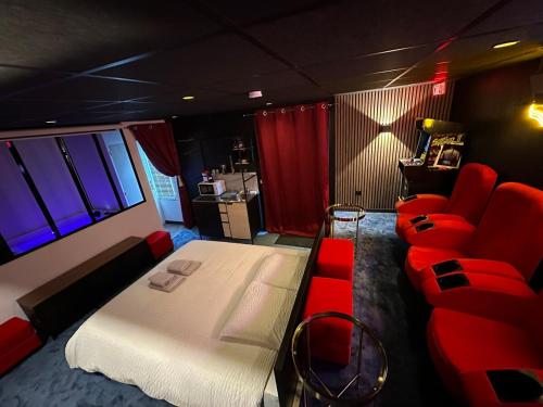 - une chambre avec un lit, un canapé et des fauteuils rouges dans l'établissement 4K cinema, Jacuzzi, à Mérignac