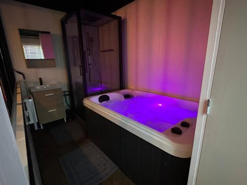 une baignoire avec des lumières violettes dans une salle de bain dans l'établissement 4K cinema, Jacuzzi, à Mérignac