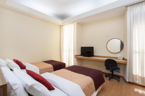 a hotel room with three beds and a mirror at Nikkey Palace Hotel in Sao Paulo