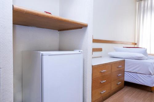 a kitchen with a refrigerator next to a bed at Nikkey Palace Hotel in Sao Paulo