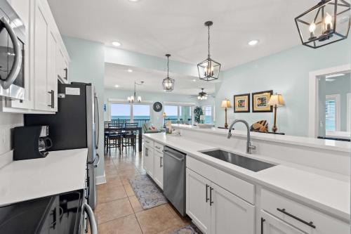 a kitchen with white counter tops and a sink at The Vue by Panhandle Getaways in Mexico Beach