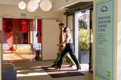 a man and woman walking down a hallway at ibis Styles Le Puy en Velay in Le Puy en Velay