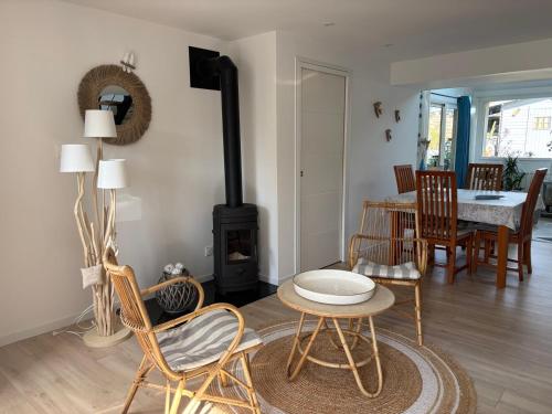 - un salon avec une cheminée, une table et des chaises dans l'établissement Les Alizés - longère rénové, à Gicquel