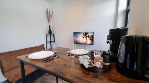 ein Holztisch mit Tellern und Gläsern darauf in der Unterkunft Studio Machy - Centre-Ville et Parking Gratuit in Bourbourg