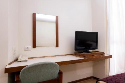 a room with a television and a mirror and a chair at Nikkey Palace Hotel in Sao Paulo