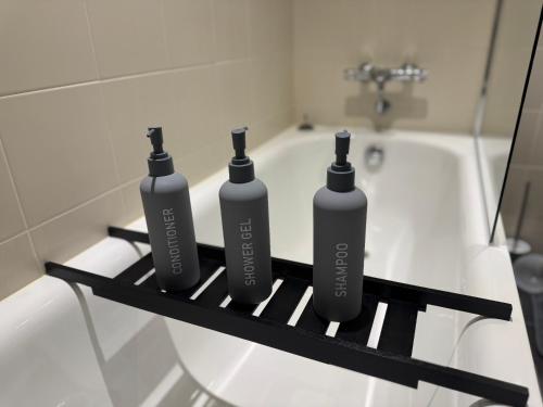 three bottles sitting on a rack next to a bath tub at NumberOne - PINK - MediaCityUK in Manchester